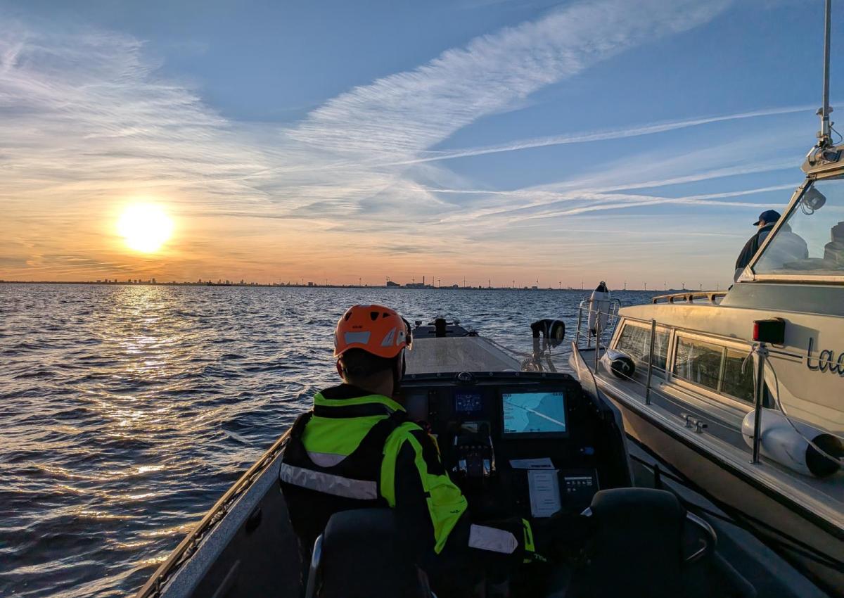 Rescue Njord med havaristen på siden sejler mod solnedgangen.